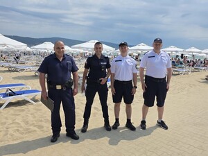 na zdjęciu widoczni są czterej umundurowani policjanci stojący na deptaku  na plaży w tle widoczne leżaki i parasole