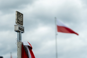 zdjęcie przedstawia zbliżenie na policyjny grot na sztandarze z napisem policja