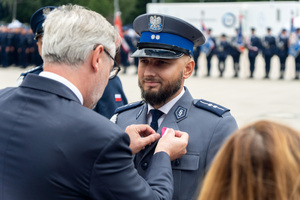 zdjęcie przedstawia ceremonię wręczania medalu policjantowi