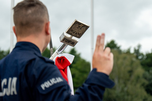 zdjęcie przedstawia ślubującego policjanta a w tle policyjny sztandar