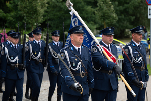 zdjęcie przedstawia maszerujących policjantów ze sztandarem