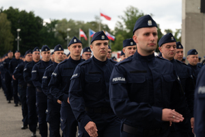zdjęcie przedstawia maszerujących w kolumnie policjantów