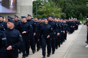 zdjęcie przedstawia policjantów maszerujących w kolumnie