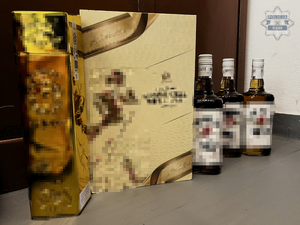 na zdjęciu widoczne dwa kartonowe opakowania  na alkohol i trzy butelki whisky ułożone na podłodze w pokoju