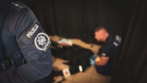 na zdjęciu widoczne na pierwszym planie ramię umundurowanego policjanta z naszywkami Policja SPPP, na drugim planie rozmazane tło i widoczny na podłodze leżący na plecach  umundurowany manekin , którego za głowę trzyma umundurowany policjant