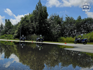 na zdjęciu widoczni na torze trzej policjanci w czarnych kombinezonach motocyklowych i białych kaskach, poruszający się na oznakowanych motocyklach służbowych z napisem policja