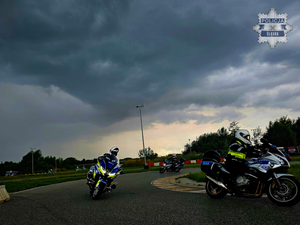 na zdjęciu widoczni na torze trzej policjanci w czarnych kombinezonach motocyklowych i białych kaskach, poruszający się na oznakowanych motocyklach służbowych z napisem policja