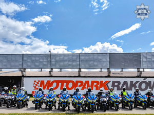 na zdjęciu widoczni usytuowani na placu przed budynkiem, w szeregu policjanci w czarnych kombinezonach motocyklowych i białych kaskach, siedzący na oznakowanych motocyklach służbowych z napisem policja, na drugim planie na budynku napis motoparkraków