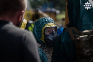 Mężczyzna w kombinezonie i masce gazowej.