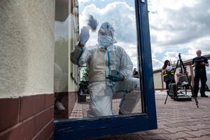 funkcjonariusz policji ubrany w kombinezon ochronny sprawdzający ślady
