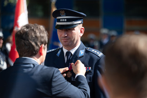 Wojewoda Śląski przypina medal policjantowi