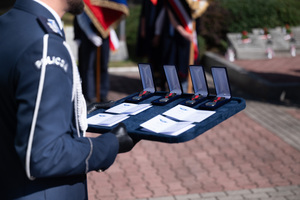 Zdjęcie przedstawia policjanta trzymającego medale na tacy