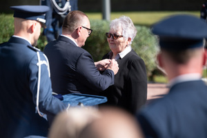 Na zdjęciu policjant oraz mężczyzna przypinający medal kobiecie