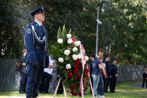 Na zdjęciu policjant kompanii honorowej stojący obok wieńca z kwiatami