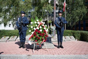 Na zdjęciu dwaj policjanci kompanii honorowej obok wieńca z biało czerwonych kwiatów