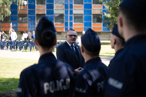 Na zdjęciu mężczyzna i policjanci na tle budynku komendy wojewódzkiej