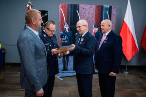 Na zdjęciu policjant oraz osoba podczas otrzymywania wyróżnienia.