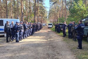 policjanci ustawieni w rzędach, dookoła nich las