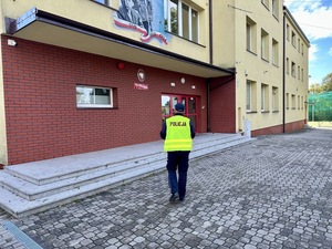 policjant idący w stronę budynku szkoły