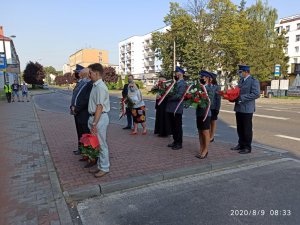 Rodzina i policjanci składający kwiaty przed tablicą pamiątkową sierż. Grzegorza Załogi