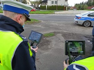 Policjanci rejestrujący obraz przy użyciu drona w okolicy przejścia dla pieszych.