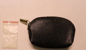 Po prawej stronie mała czarna torebka zapinana na suwak, po lewej stronie woreczek z zawartością białej substancji