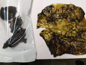 Zdjęcie przedstawia po lewej stronie w woreczku strunowym przedstawia zabezpieczoną czarną substancję koloru czarnego. Po prawej stronie widoczna folia, w którą była zawinięta substancja.