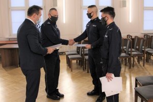 Komendant Powiatowy Policji w Będzinie oraz Starosta Będziński stoją przez dwoma umundurowanymi policjantami dziękując im za swoją postawę.