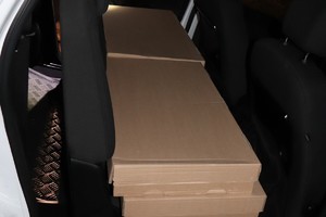 Kartony ułożone na tylnej kanapie samochodu.