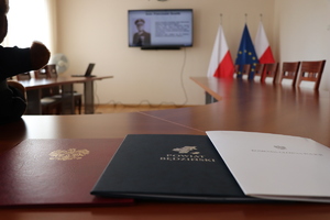 Na zdjęciu widoczny telewizor na którym odtwarzana jest konkursowa praca uczniów, po prawej stronie znajdują się flagi Polski i Unii Europejskiej.
