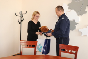 Komendant Powiatowy Policji w Będzinie przekazuje mamie wyróżnionego chłopca wyróżnienie i maskotkę policyjną.