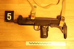 Na zdjęciu widoczny czarny pistolet maszynowy, obok którego znajduje się numer 5, a pod nim skalówka kryminalistyczna.