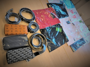 Na zdjęciu widać rozłożone na biurku zapakowane koszulki różnych marek, paski i portfele.