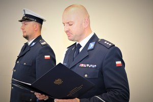 Zdjęcie przedstawiające policjanta w mundurze, który odczytuje rozkaz.