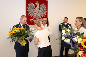 Na zdjęciu kobieta wręczająca kwiaty nowemu Komendantowi Powiatowemu Policji w Będzinie.