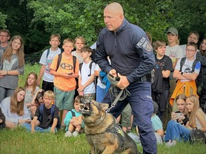Zdjęcie, na którym policjant trzyma policyjnego psa.
