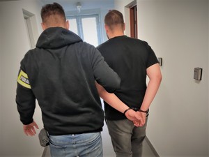 Na zdjęciu policjant prowadzi zatrzymanego mężczyznę.