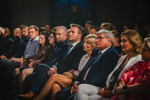 Zdjęcie grupowe przedstawiające osoby zasiadające w pierwszym rzędzie podczas spektaklu &quot;Sekret&quot; w teatrze.