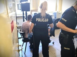 Na zdjęciu policjantka i siedzący na krześle zatrzymany.