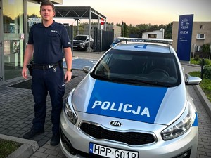 Na zdjęciu policjant przy radiowozie.