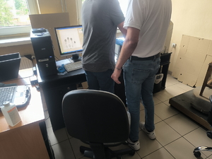 Na zdjęciu zatrzymany mężczyzna ma pobierane odciski palców przez technika kryminalistyki.