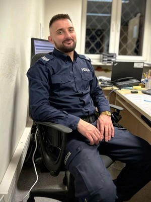 Na zdjęciu policjant w mundurze, który siedzi w gabinecie.