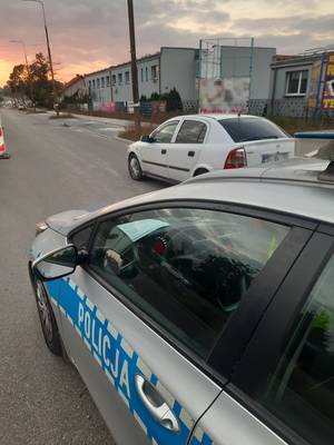 Na zdjęciu radiowóz i biały opel na drodze.