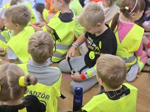 Na zdjęciu zbliżenie na grupę dzieci w elementach odblaskowych.