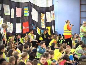 Na zdjęciu grupa dzieci w elementach odblaskowych oraz policjantka i policjant.