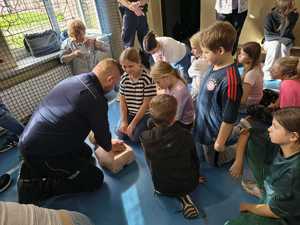Na zdjęciu policjant z dziećmi podczas nauki pierwszej pomocy