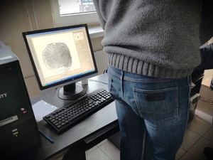 Na zdjęciu zbliżenie na technika kryminalistyki pobierającego odciski palców od zatrzymanego.