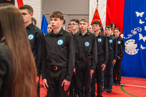 Na zdjęciu grupa uczniów w czarnych koszulach podczas uroczystego ślubowania.