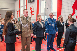 Na zdjęciu zaproszeni goście wręczają uczniom biało-czerwone opaski.