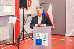 Na zdjęciu kobieta, która jest członkiem zarządu powiatu będzińskiego zabiera głos przy mównicy.